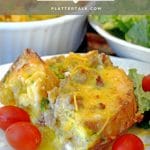 Serving of overnight breakfasgt casserole on a plate with cherry tomatoes.