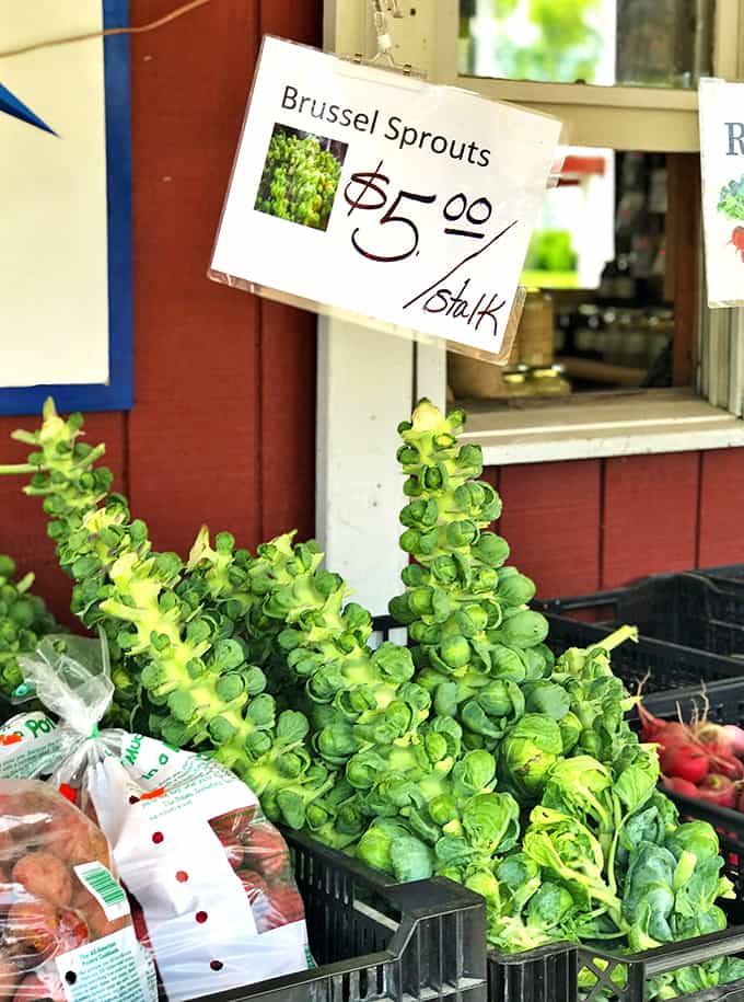 A produce section of a farmer\'s market with fresh Brussels sprouts