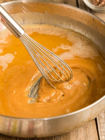 A whisk stirring a roux in a skillet