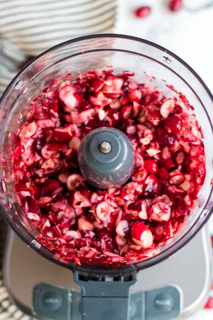 Chopping fresh cranberries for cranberry salad using a food processor.