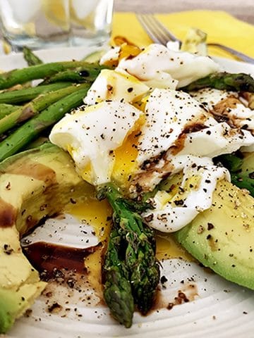 A close up of a plate of food with asparagus, with Avocado and Egg