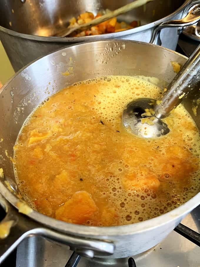 An immersion blender in a pot of soup