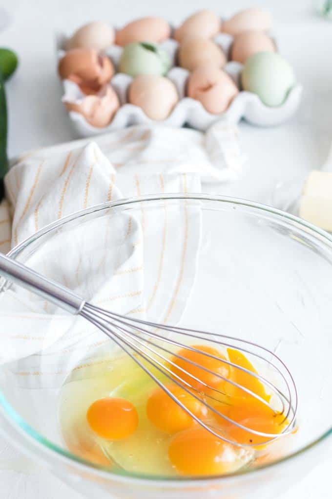 A bowl of eggs and a whisk