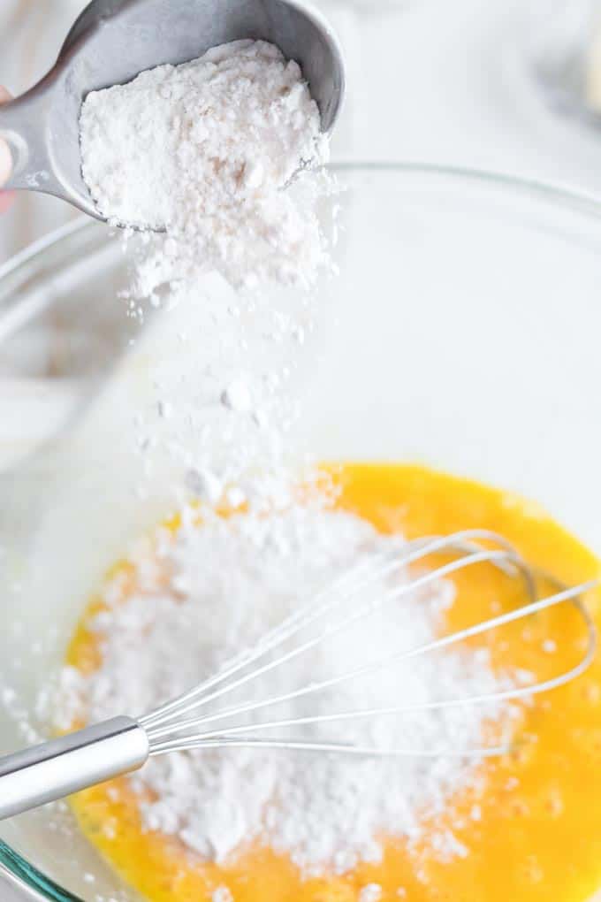 Adding flour to eggs in a mixing bowl