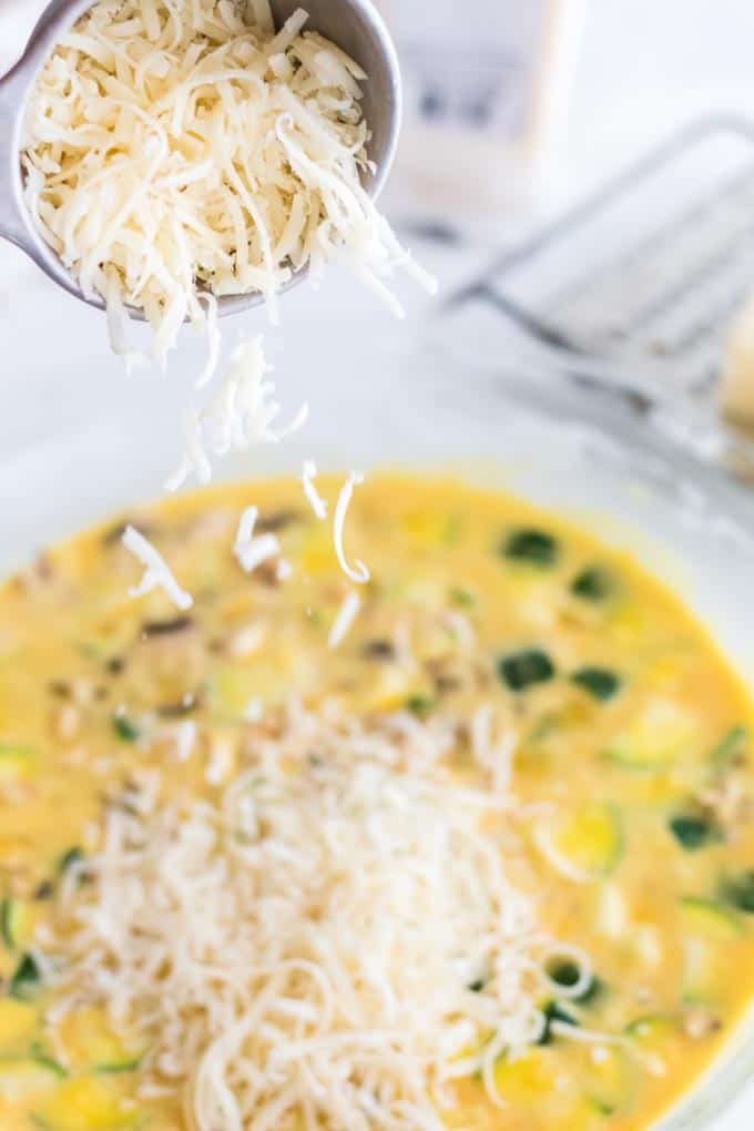 Adding shredded cheese to a mixing bowl