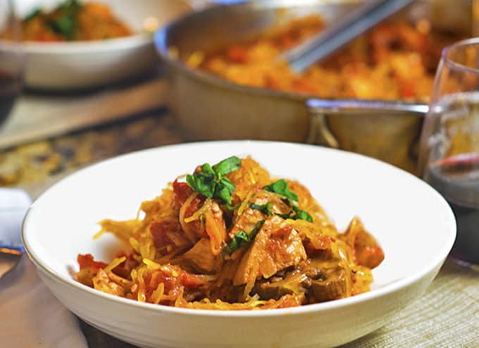 A bowl of food on a plate on a table, with Spaghetti squash and Chicken