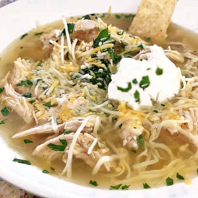 A plate of food, with chicken soup and sour cream on top