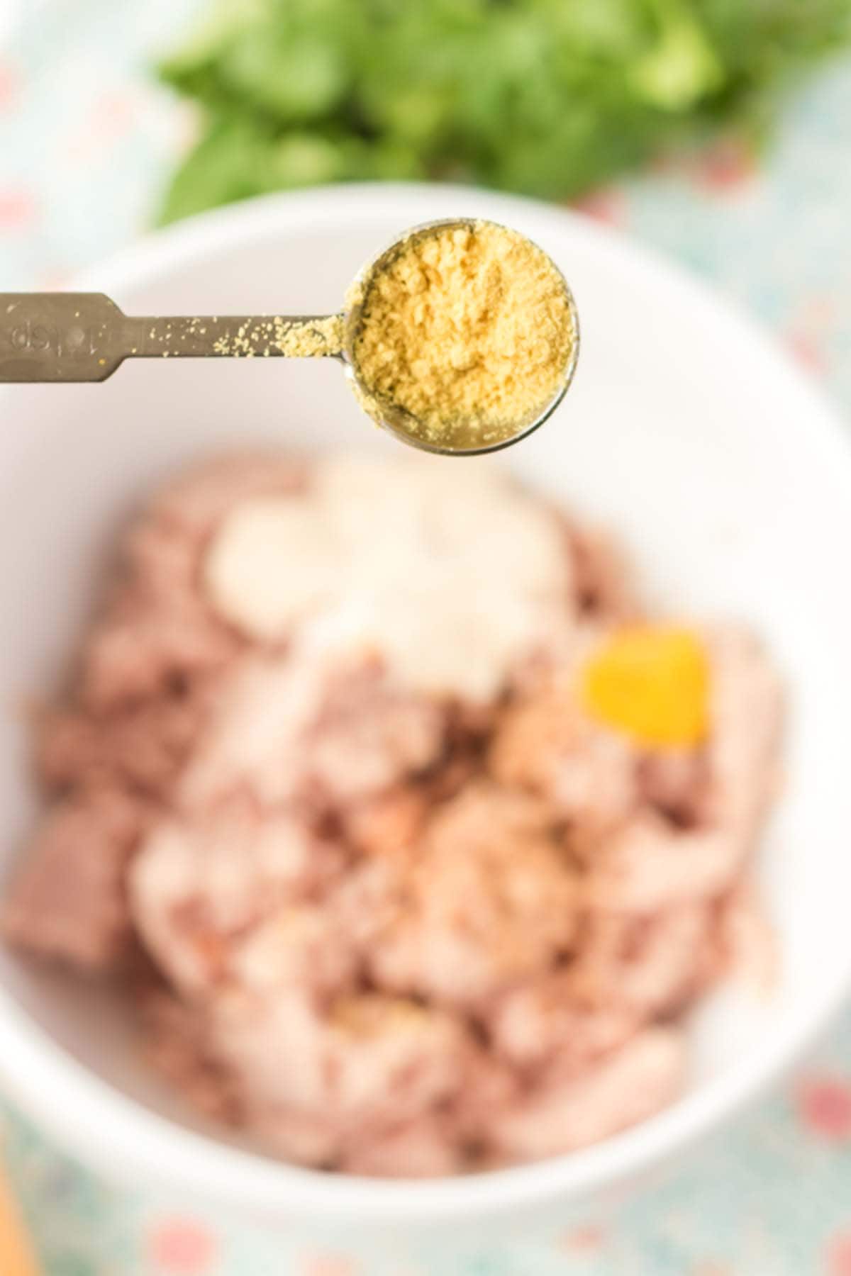 Adding some dry mustard to a bowl of chopped up ham.