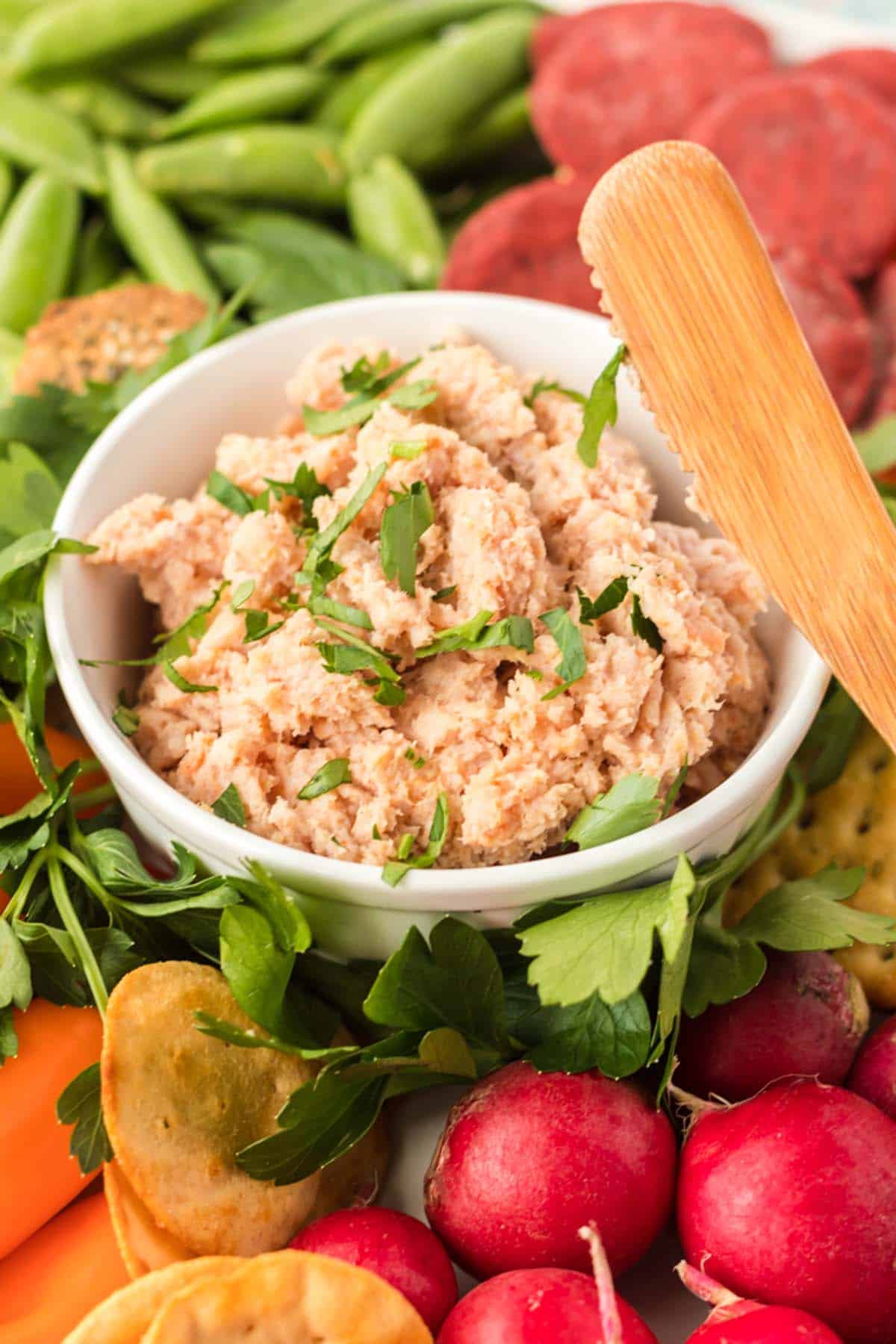 A bowl of deviled ham surrounded by veggies.