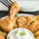 Polish dumpling on fork being dipped in sour cream.