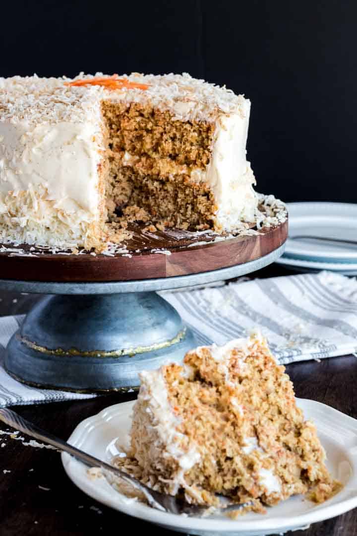 Slice of homemade carrot cake and cut cake in the background.