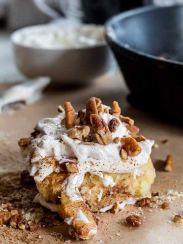 A keto cinnamon roll topped with sugar free frosting and chopped nuts.
