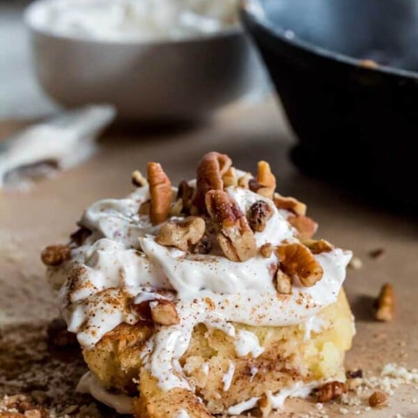 A keto cinnamon roll topped with sugar free frosting and chopped nuts.