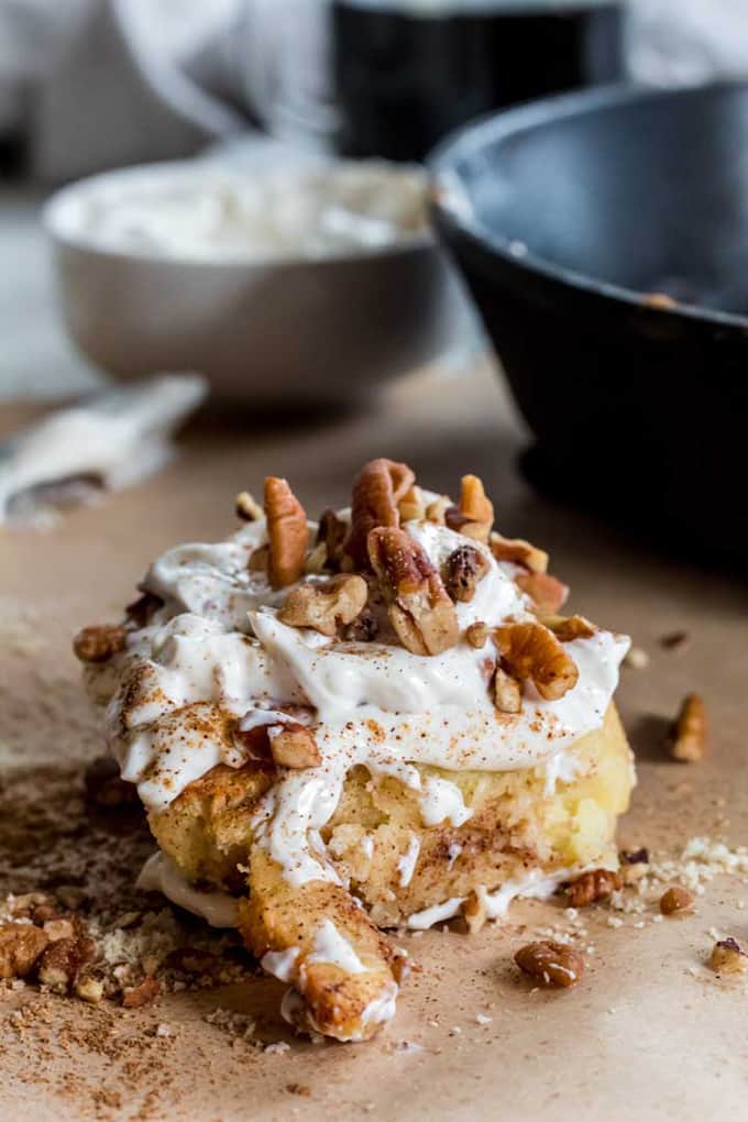 A keto cinnamon roll topped with sugar free frosting and chopped nuts.