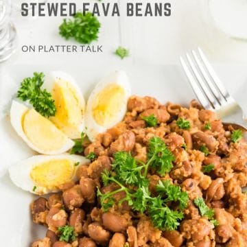 Plate of stewed fava beans with hard-boiled egg and parsley.