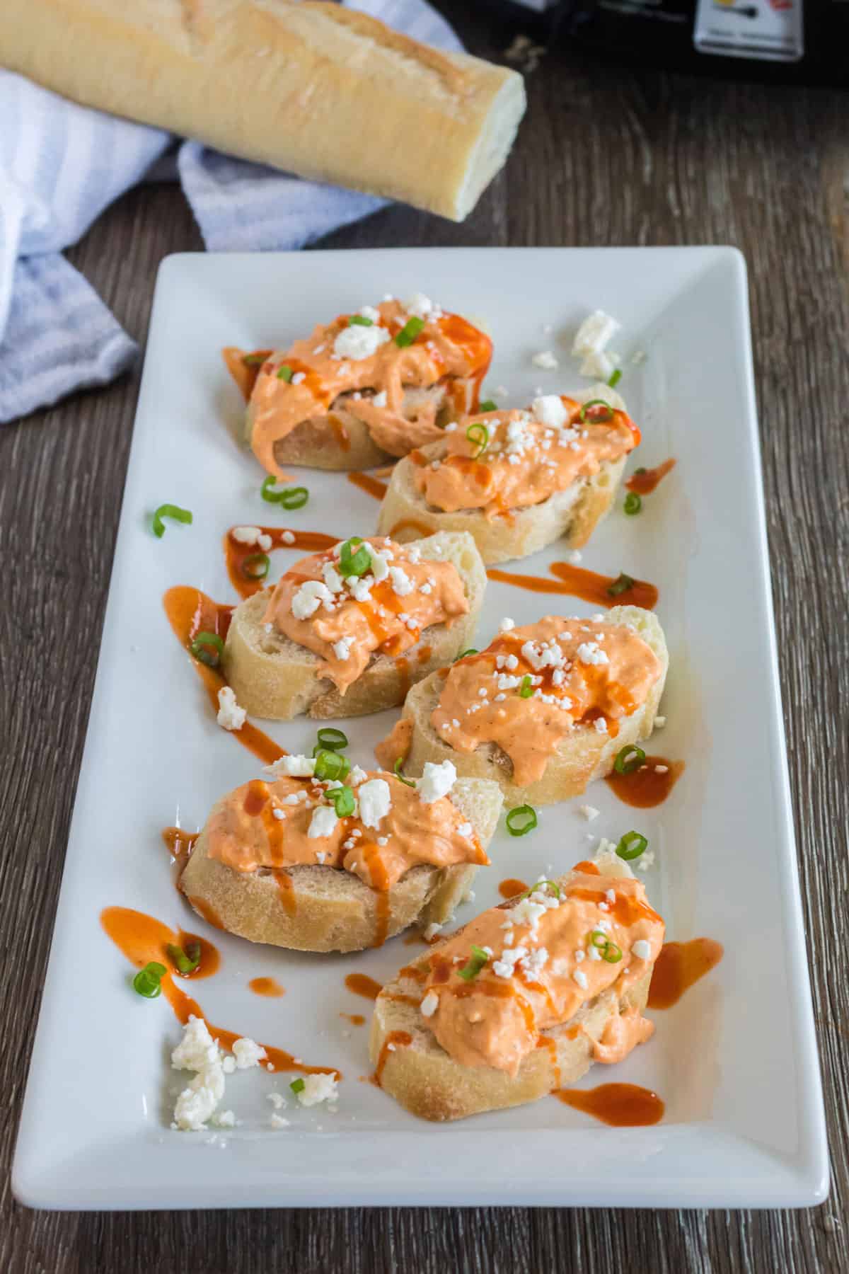 A plate of crostini and Buffalo Wings Dip.