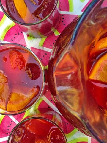 Pitcher of sangria with three glasses.