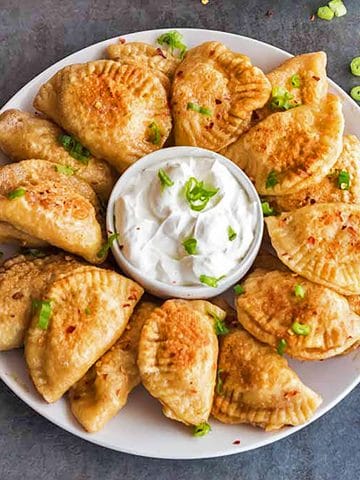 Round plate of Polish dumplings with sour cream.