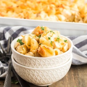 Bowl of baked pasta shells with chicken casserole in the background.