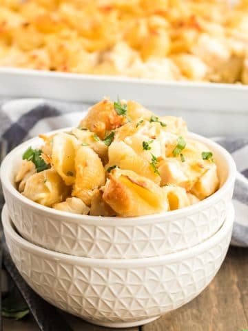 Bowl of baked pasta shells with chicken casserole in the background.