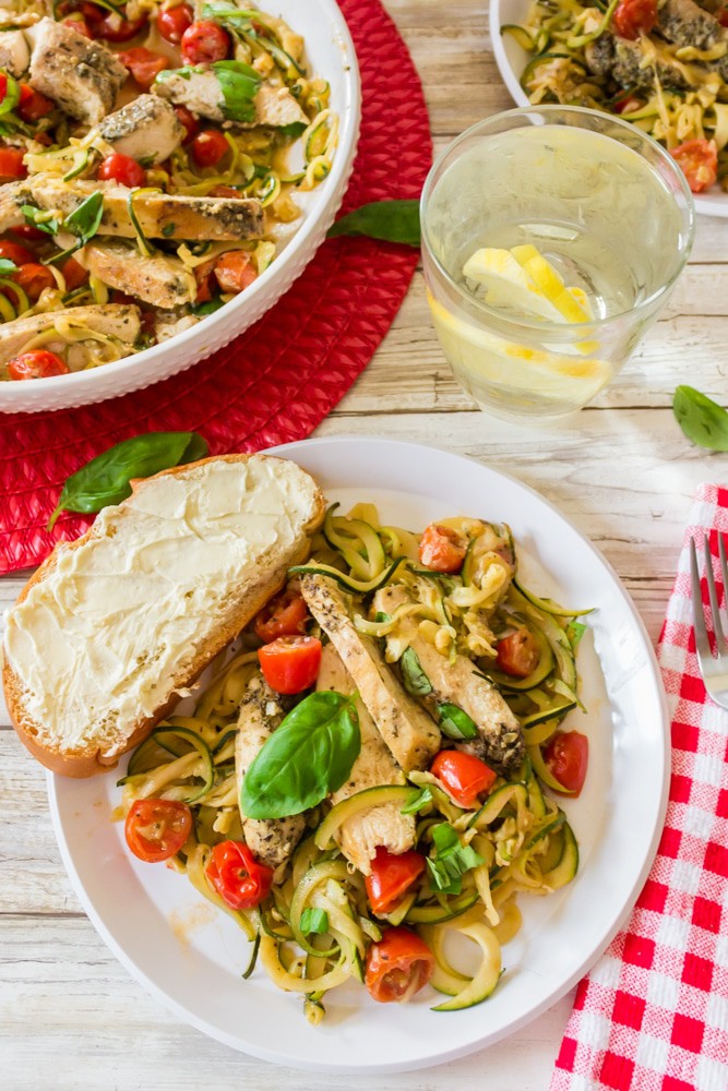 Serving of zucchini noodles with chicken and a glass of ice water.