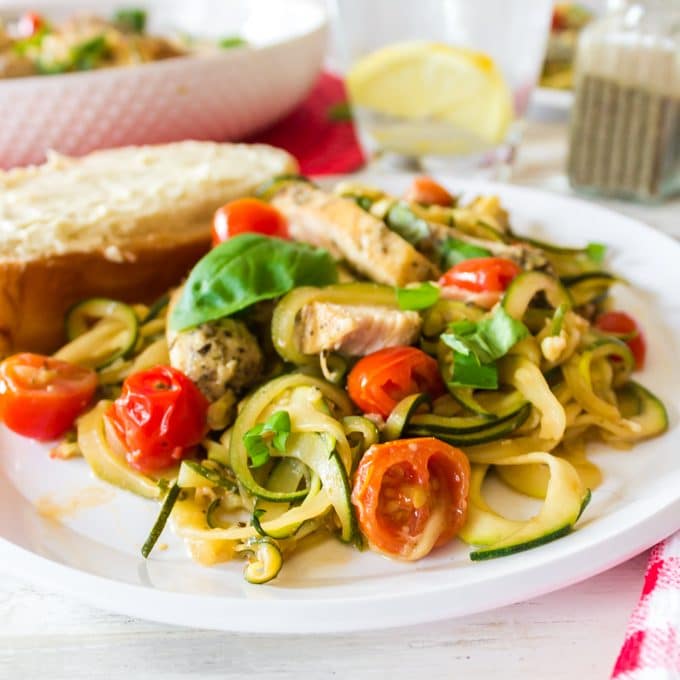 A serving of chicken and zucchini pasta. Plate of food with cherry tomatoes and chicken.