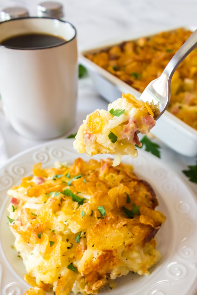 Fork of cheesy hashbrown casserole with a cup of coffee.