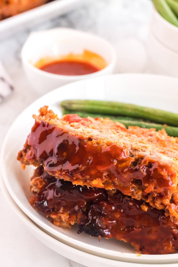Serving plate with two slicres of meatloaf on it with green beans.