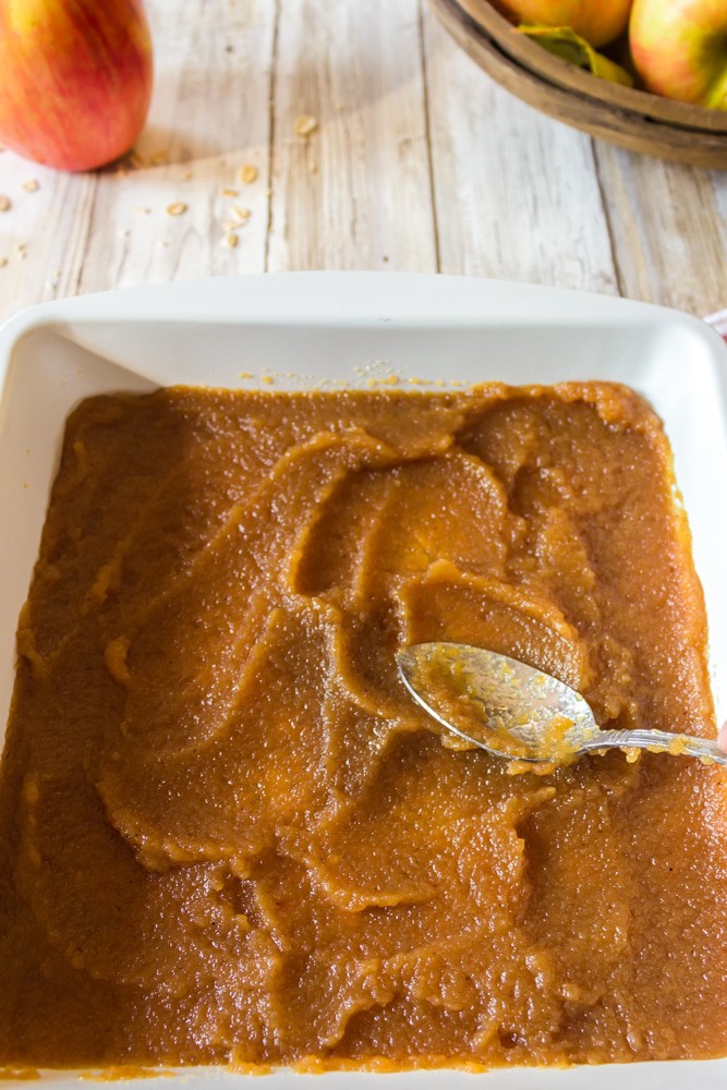 spreading apple butter over oat bars in a baking pan.