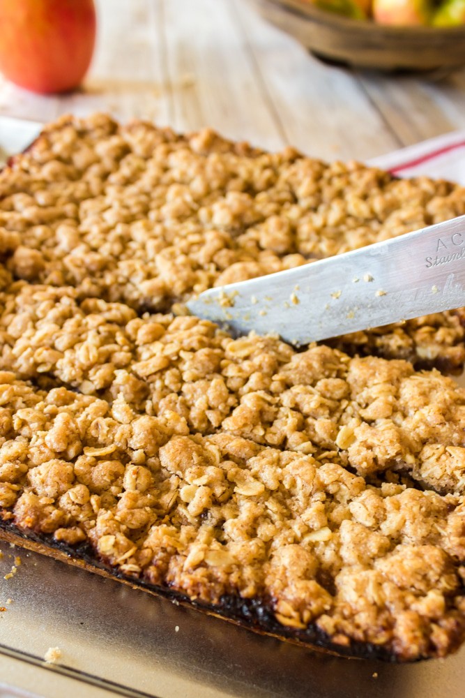 Cutting a pan full of oatmeal bars with a knife.