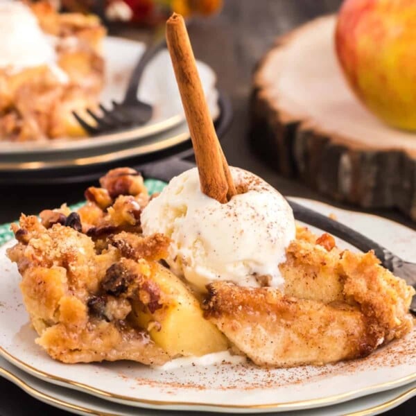 Dutch apple pie on a plate with ice cream and a cinnaomn stick.