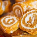 Pumkin roll cake sliced on a cutting board.