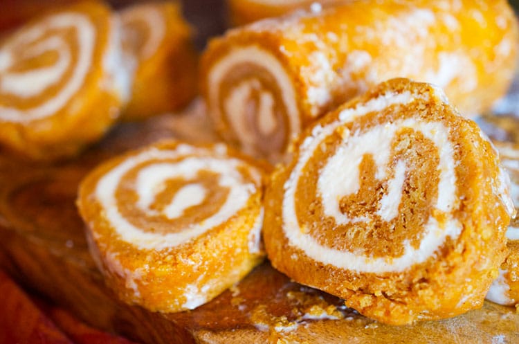 Pumkin roll cake sliced on a cutting board.