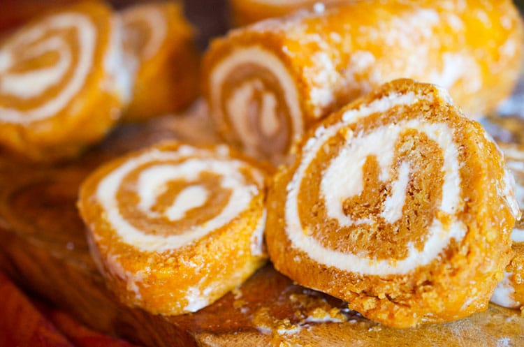 Pumkin roll cake sliced on a cutting board.