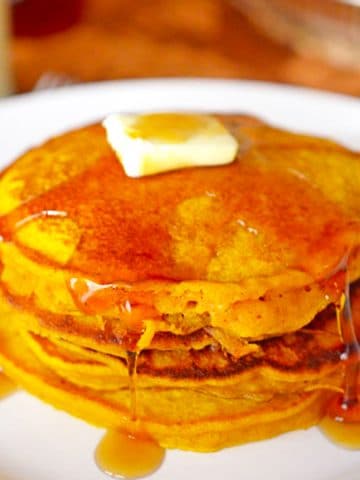 A stack of pancakes drizzled in syrup