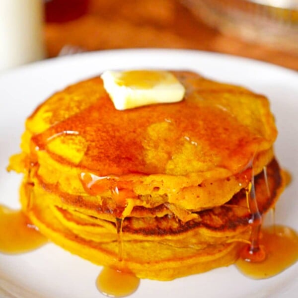 A stack of pancakes drizzled in syrup