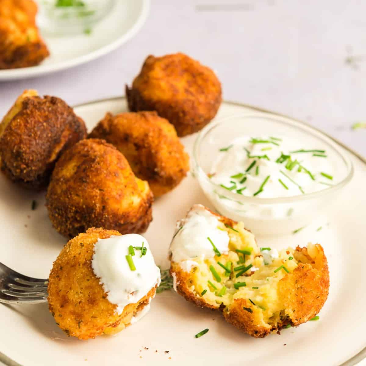 Plate of mashed potato croquettes with sour cream and chves.