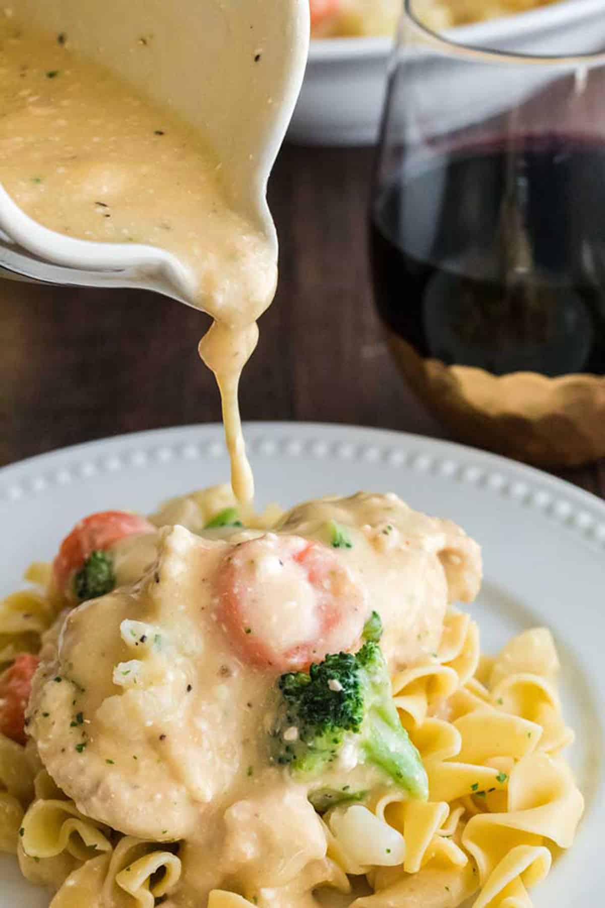 Pouring cream sauce on a piece of chicken.