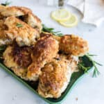 A serving platter of chicken garnished with rosemary sprigs.