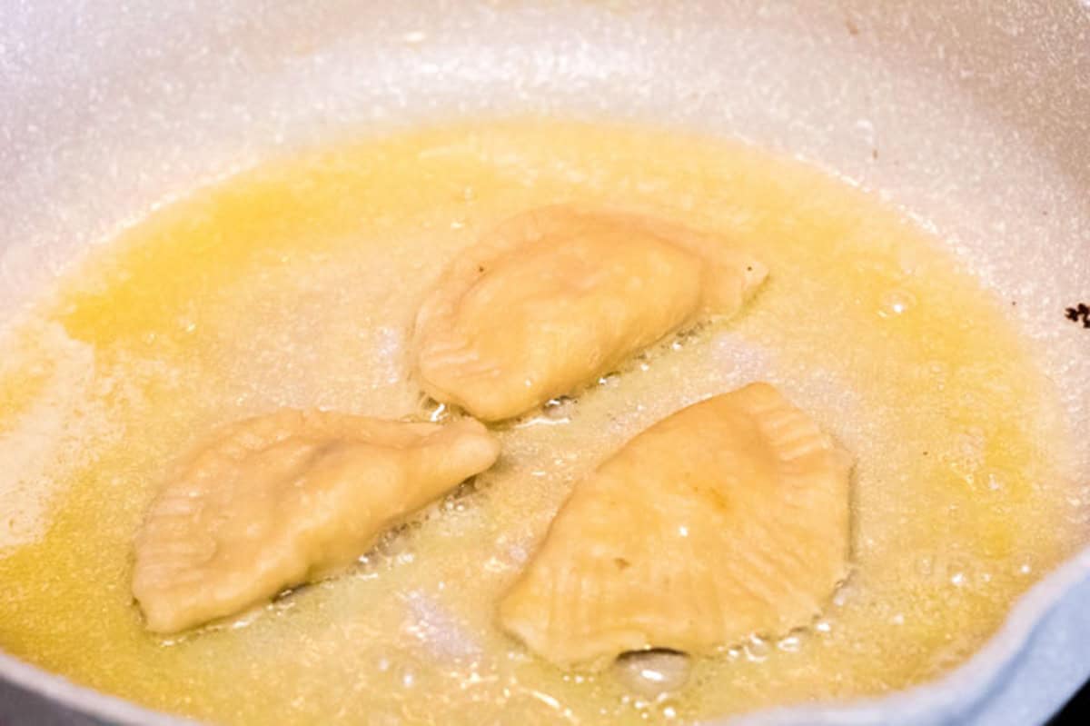 Sauteing pierogi in a skillet with butter.