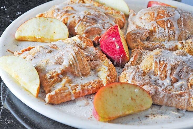 Plate of apple turnovers with slices of apple.