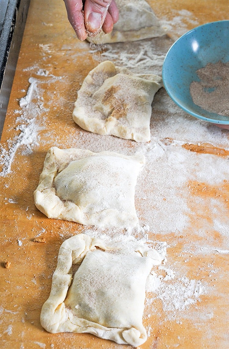 Sprinling sugar and cinnamon on crescent roll dough