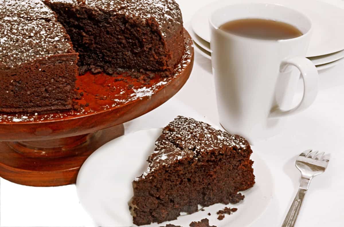 A chocolate cake with a piece cut out and a cup of coffee.