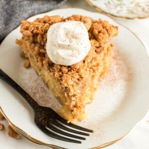 A slice of apple dessert on a plate with sour cream topping