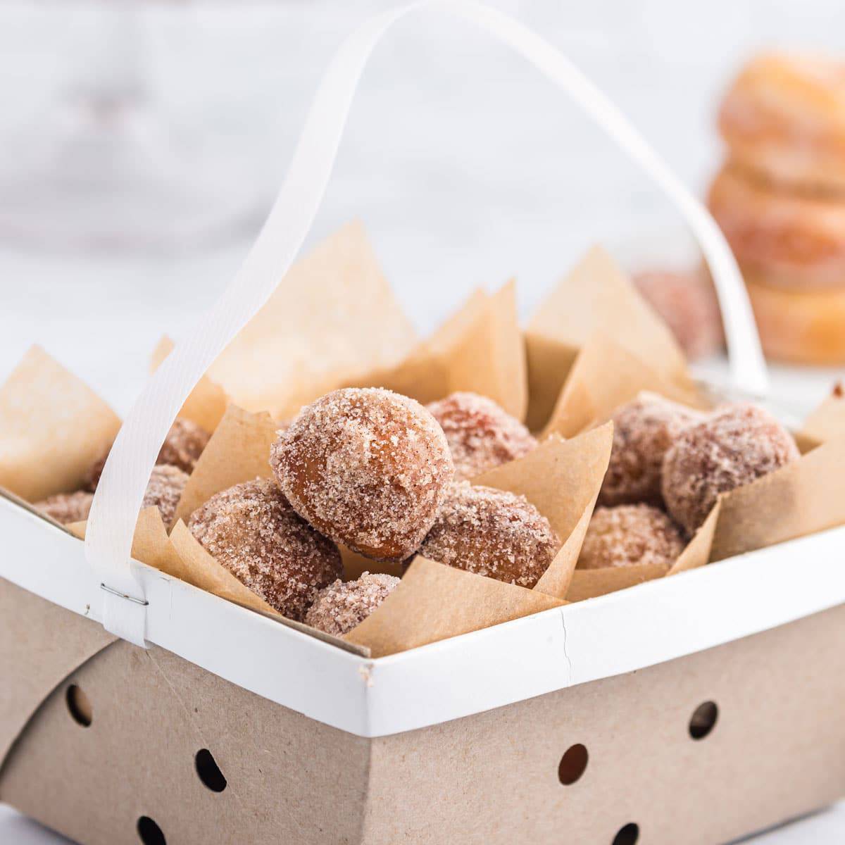 A box of donut holes coated with sugar.