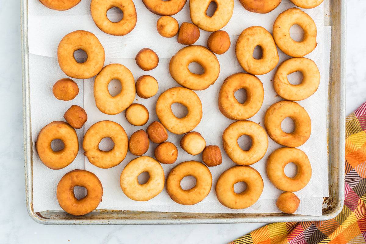 A bunch of donuts on a baking sheet lined with parchment paper
