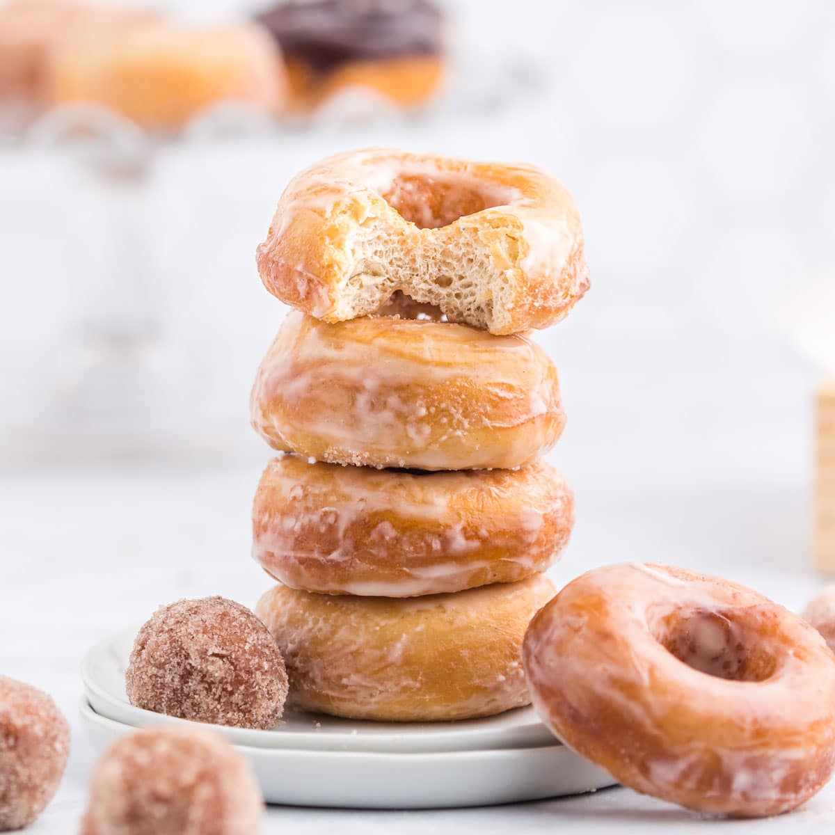 A stack of glazed, raised donuts on a plate.