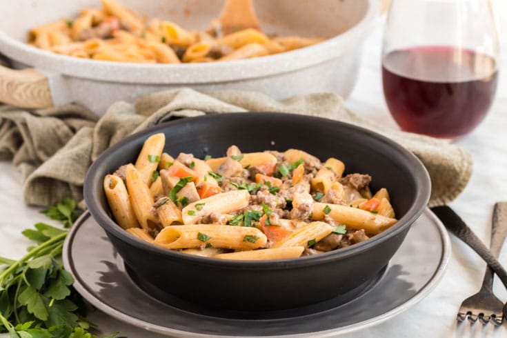 Bowl of healthier hamburger stroganoff with glass of red wine.