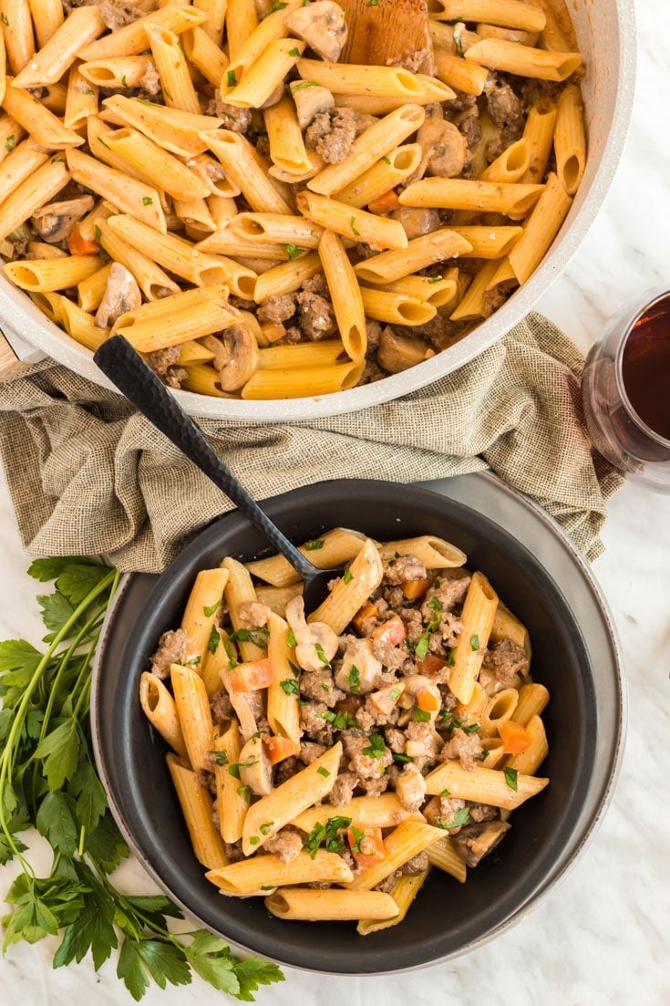 Skillet of beef and pasta and a filled serving bowl.