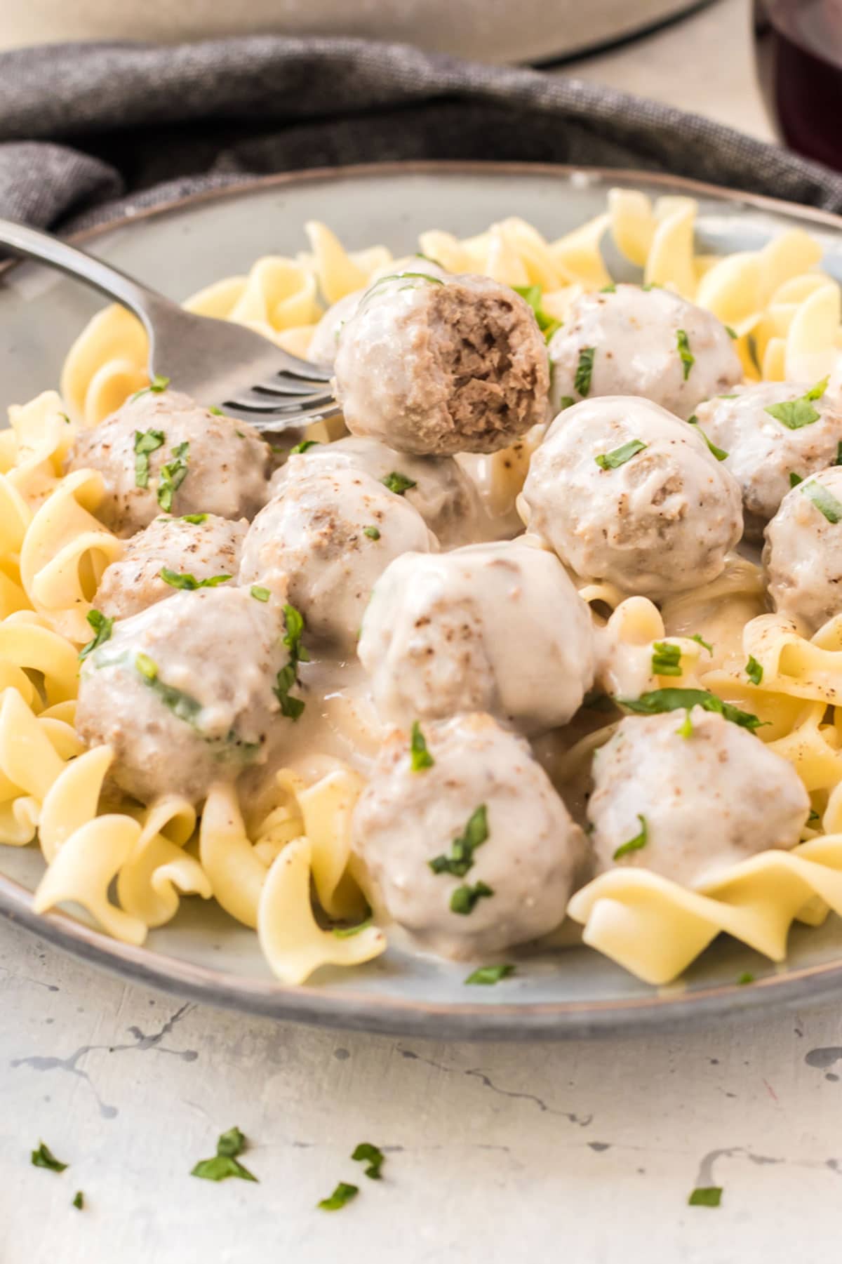 A fork with a plate of meatballs on noodles.